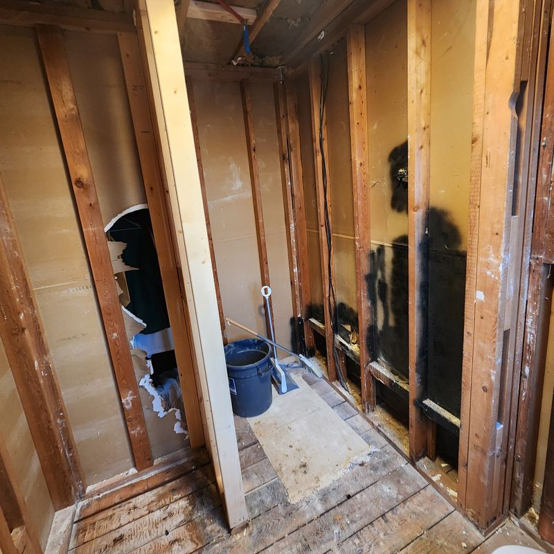 The shower side gutted to the studs, debris on the subfloor