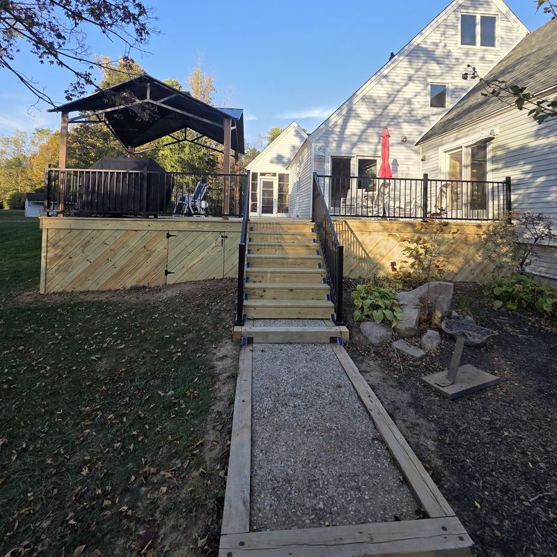 New stairs with black railings down to a re-edged gravel path