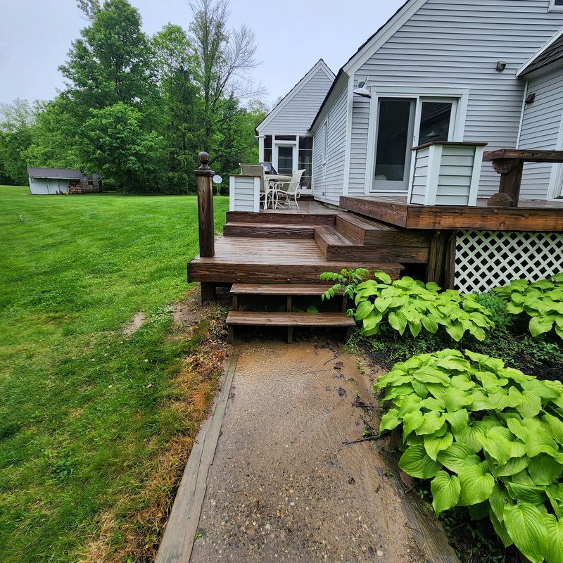 Old deck steps down to a worn gravel path