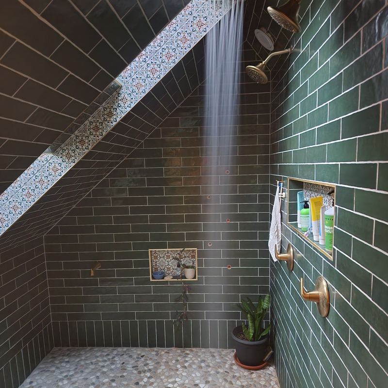 The finished walk-in shower running, brass rain head and handles, plant in the corner